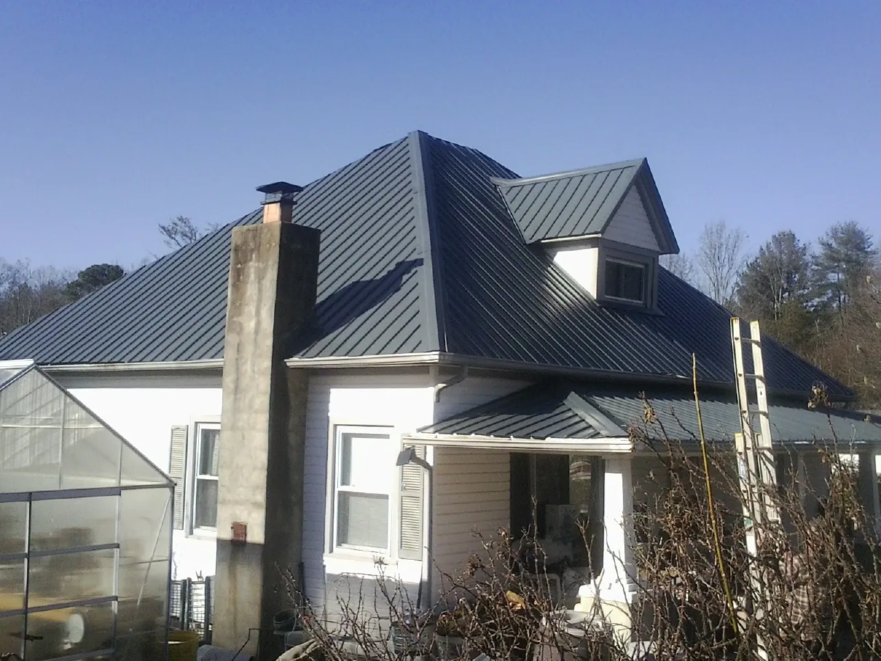 Dark blue standing seam metal roof on a white farmhouse with dormer — Slate & Tile Roof Repair by Roofing Brothers in Filer
