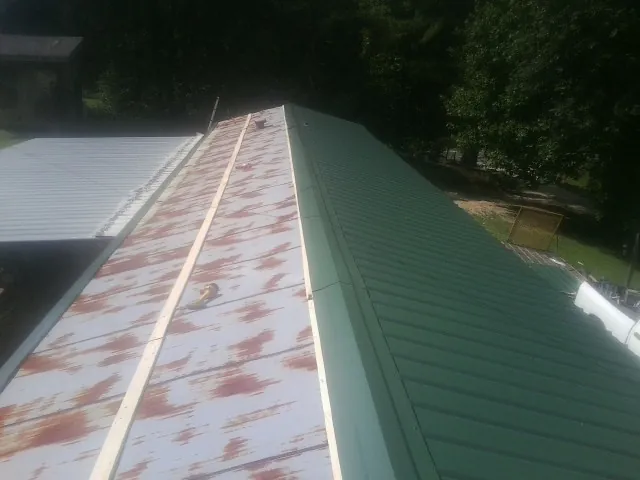 Old rusted panels beside newly installed green metal roofing — Wind Damage Roof Repair by Roofing Brothers in Filer
