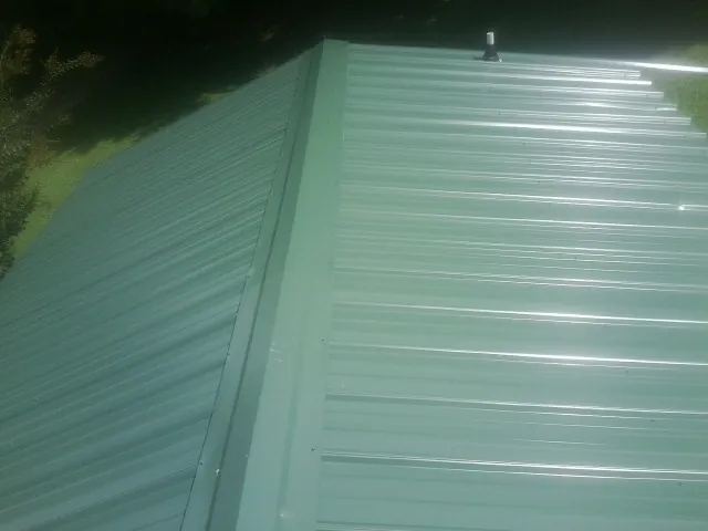 New green metal panels meeting at the ridge of a roof — Flat Roof Repair work by our crew in Filer