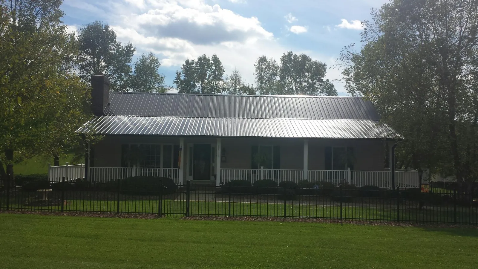 Gray metal roof on a brick ranch with a full width front porch — Gutter Guard Installation work by our crew in Filer